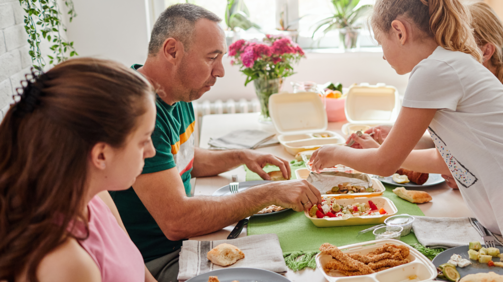 A family sits at their dining room table with their takeout food
