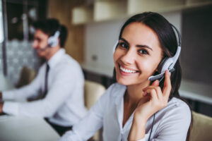 Smiling woman looks at camera while pressing her fingers to her headset