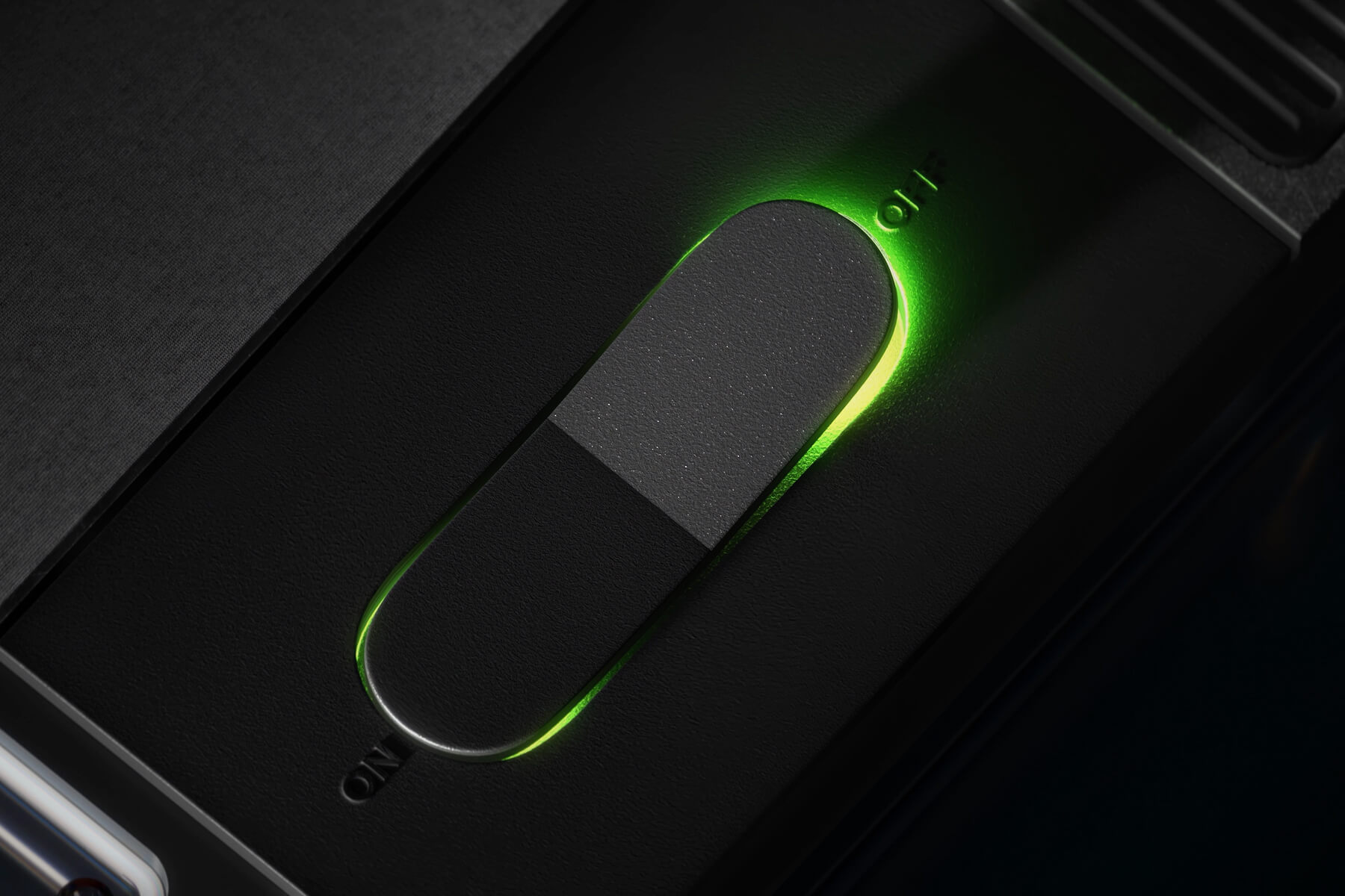 A close-up of a black switch glowing green, positioned to the ON side, with ON and OFF labels visible on either end of the switch.