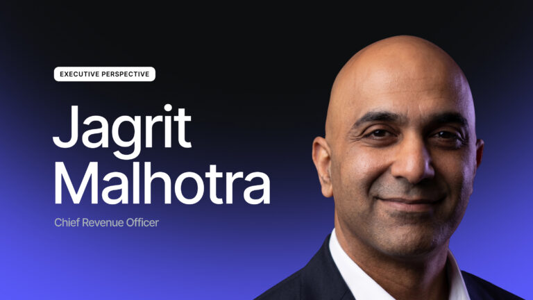 Un uomo in giacca e cravatta sorride alla telecamera, con una didascalia accanto a lui che recita “Prospettiva dirigenziale, Jagrit Malhotra, Chief Revenue Officer” su uno sfondo scuro sfumato.